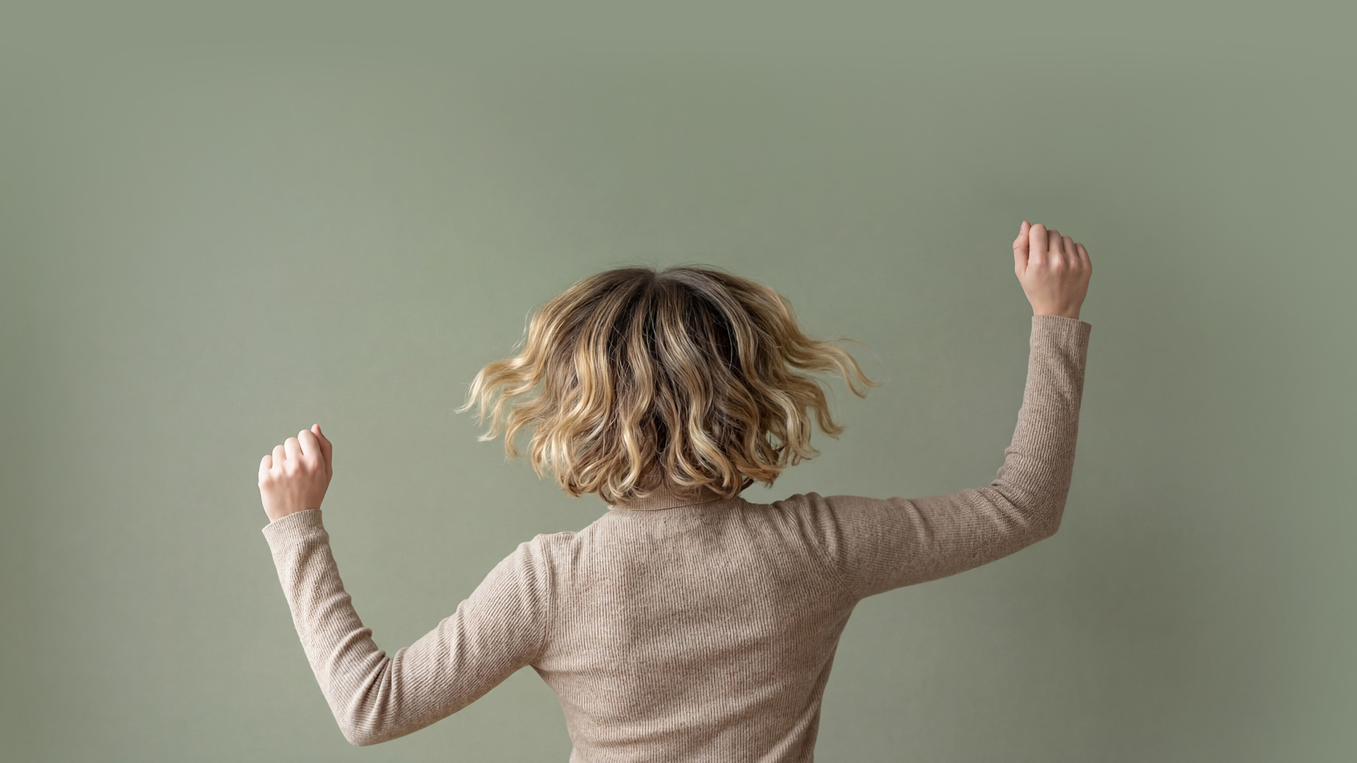 Headerbild zeigt eine Frau, die beide Arme in die Höhe hebt, während ihre voluminösen Haare schwungvoll fallen – Friseurin Lanzingen